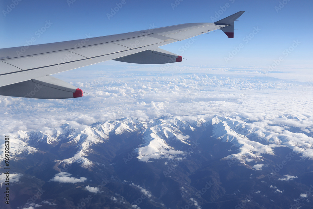 Obraz premium Airplane flying above the Fagaras mountains covered with snow. Photo taken through the airplane window.