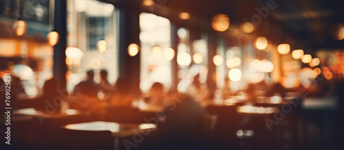In this blurry image  a restaurant setting is captured  with various individuals seated at tables. The scene depicts a bustling dining environment with blurred outlines of people engaging in