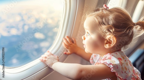Curious little girl traveling by airplane, sitting by window and admiring the view outside