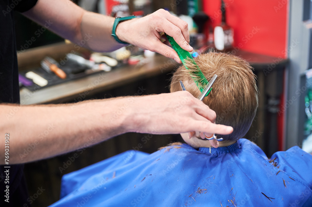 Man barber cutting little boy's hair using comb and scissors. Child getting haircut from adult male, likely barber. Professional hairdresser and cute client at modern barbershop. Man barber cutting little boy's hair using comb and scissors. Child getting haircut from adult male, likely barber. Professional hairdresser and cute client at modern barbershop.