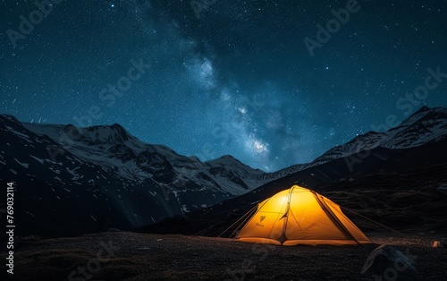 A glowing tent under the mesmerizing Milky Way, surrounded by tranquil mountainous terrain. © burntime555