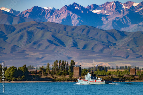 A boat on the water of the famous Issyk-Kul lake surrounded by the Ala-Too mountains. Kyrgyzstan, July 2023 photo