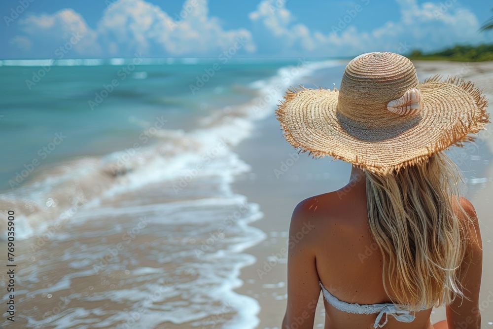 A blonde woman wearing a straw hat looks out at the ocean horizon, embodying concepts of contemplation and wanderlust