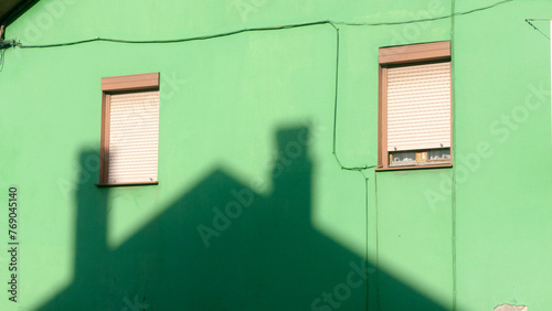 Sombra de tejado de casa sobre fachada de casa verde
