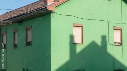 Sombra de tejado de casa sobre fachada de casa verde