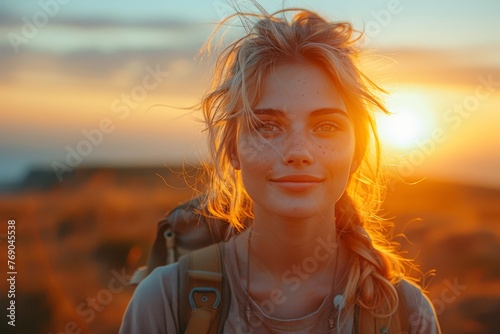Attractive young woman with braids and freckles, smiling in golden light of sunset with nature in the background