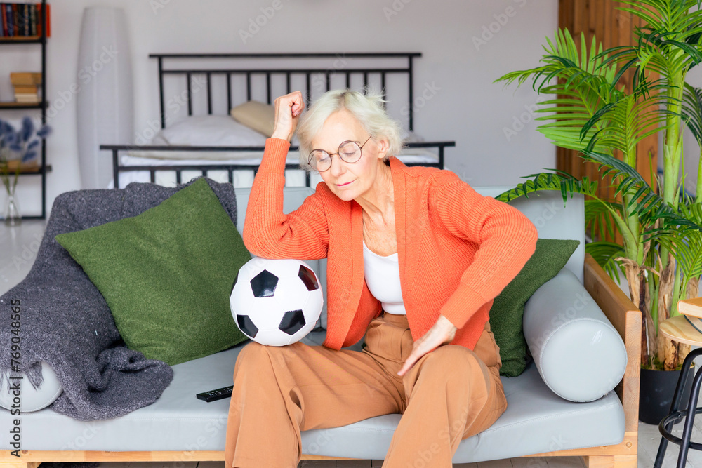 beautiful elderly senior woman in cosy apartment watching a football match, beautiful gray haired woman with soccer ball, concept of active old age beautiful elderly senior woman in cosy apartment watching a football match, beautiful gray haired woman with soccer ball, concept of active old age