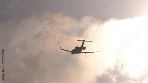 Small private plane flying in backlight, silhouette against the sun. Airplane take off, climb