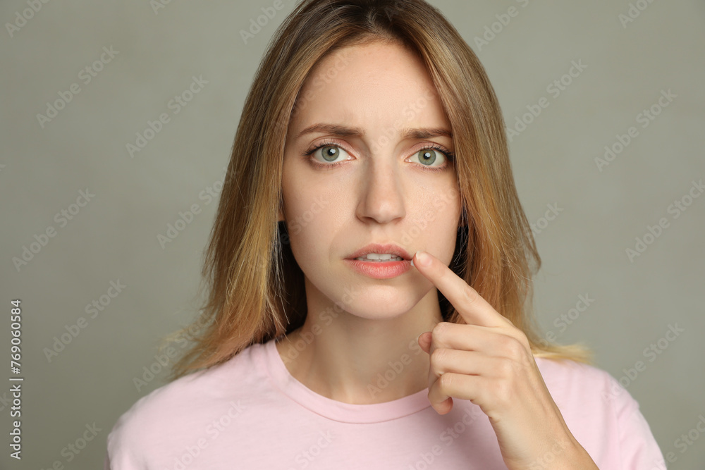 Woman with herpes applying cream onto lip against light grey background Woman with herpes applying cream onto lip against light grey background