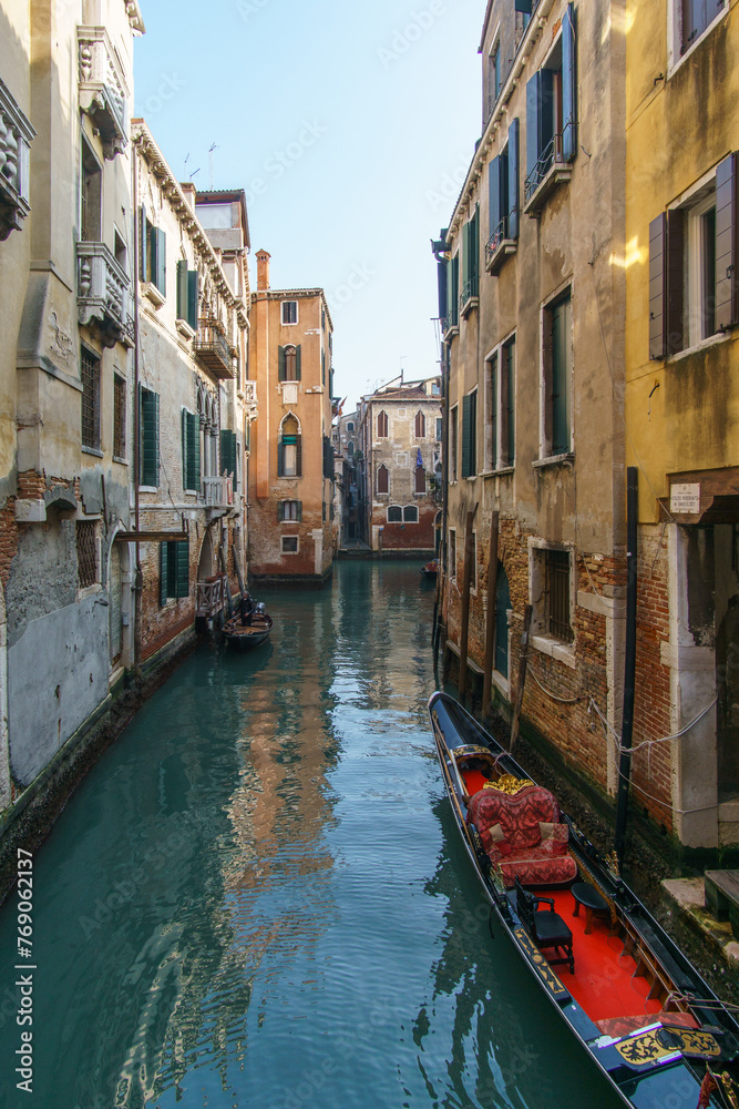 Typical narrow canal surrounded by buildings with a gondola boat in Venice, Veneto, Italy