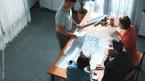 Top view of interior designer planing building while project manager working and holding coffee. Group of engineer brainstorming idea and designing house structure while presenting idea. Symposium. photo