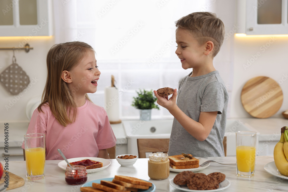 Little children having fun during breakfast at table in kitchen Little children having fun during breakfast at table in kitchen