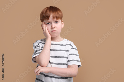 Portrait of sad little boy on beige background
