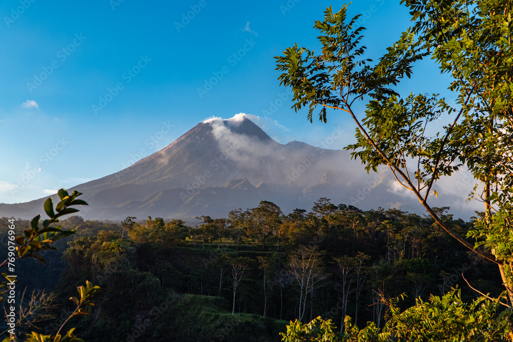 Very clear panorama of Mount Merapi in the evening with grass and fallen trees in the foreground. Mount Merapi in Yogyakarta, Indonesia is truly enchanting in the evening