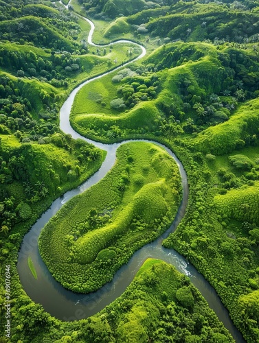 The peaceful green river winds elegantly through undulating hills, creating a harmonious natural pattern as viewed from the skies..
