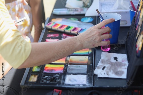 a person doing art work on a table outside at an outdoor event