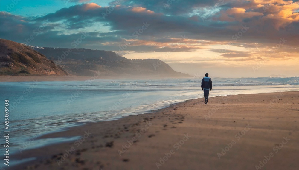 distant lonely man walking on the beach at dusk