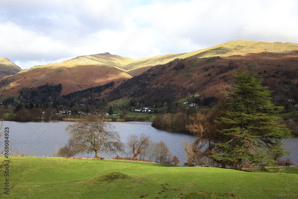 Great Rigg and Rydal Fell over Grasmere. A gloomy day in Winter and bright sun lights up the fell tops.