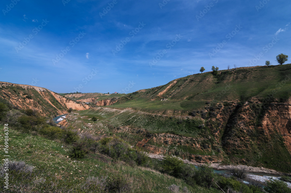 Landscape with canyon and Aksu river in Kazakhstan in spring under blue sky