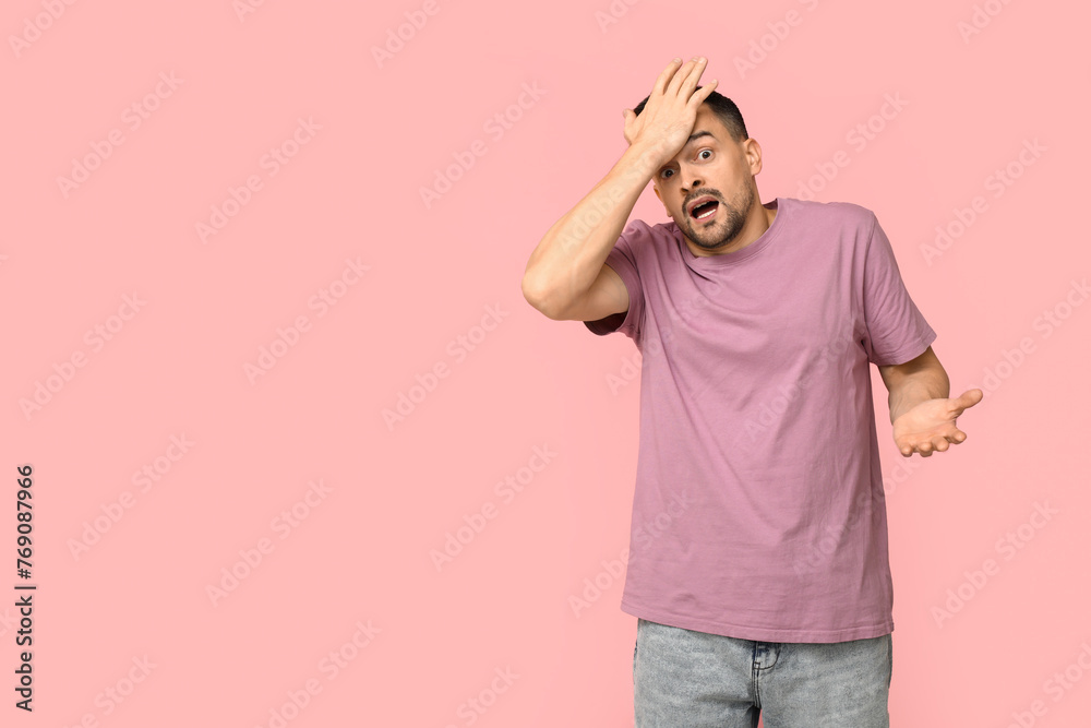 Handsome worried young man covering face with hand on pink background Handsome worried young man covering face with hand on pink background