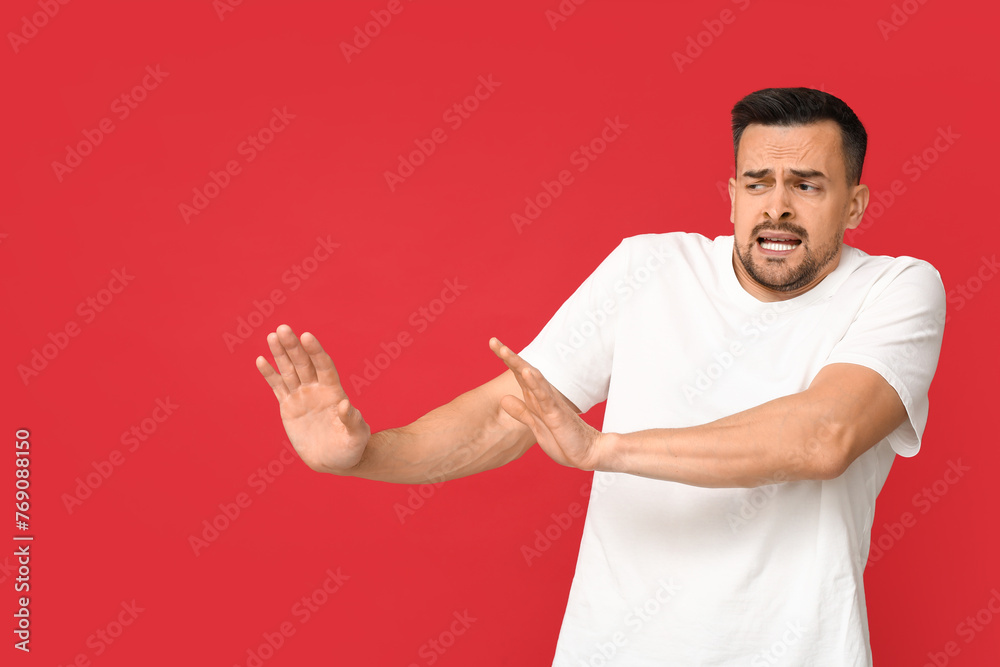 Handsome ashamed young man on red background Handsome ashamed young man on red background