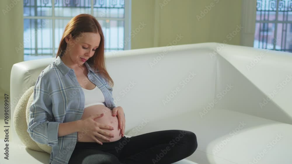 Pregnancy motherhood people expectation future. Pregnant woman touching big belly sitting on couch at home. Girl hugging her tummy enjoying pregnancy. Maternity tenderness parenthood new life concept Pregnancy motherhood people expectation future. Pregnant woman touching big belly sitting on couch at home. Girl hugging her tummy enjoying pregnancy. Maternity tenderness parenthood new life concept