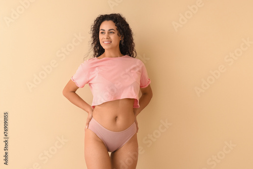 Young African-American woman in menstrual panties on beige background © Pixel-Shot
