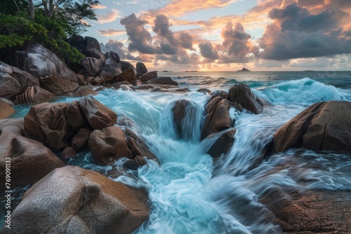 Waterfall cascading on rocky beach at sunset, a natural wonder