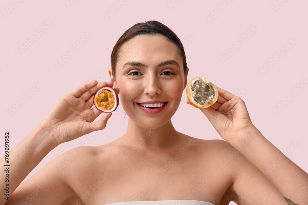 Beautiful young woman with tasty passion fruit on pink background