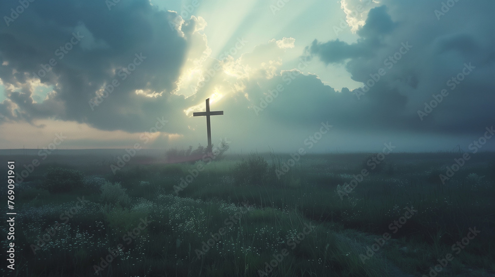 Obraz premium A cross standing alone in a field with rays of sunlight breaking through clouds