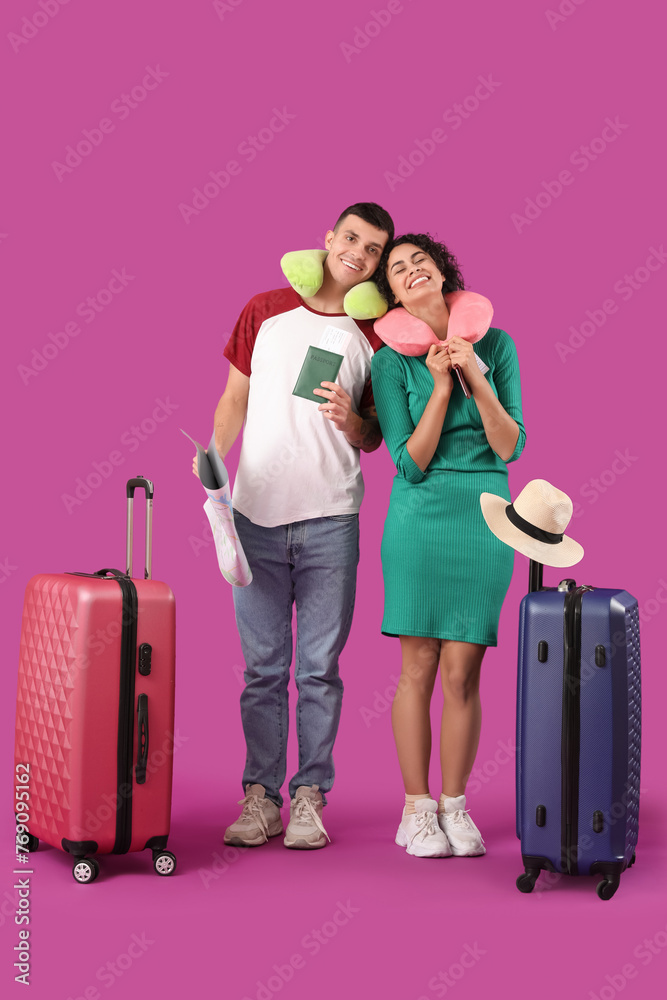 Couple of tourists with suitcases and neck pillows on pink background Couple of tourists with suitcases and neck pillows on pink background