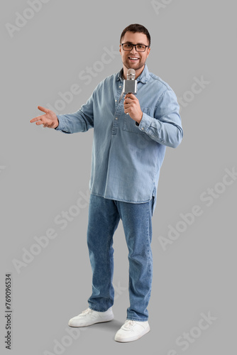 Male journalist with microphone talking on light background