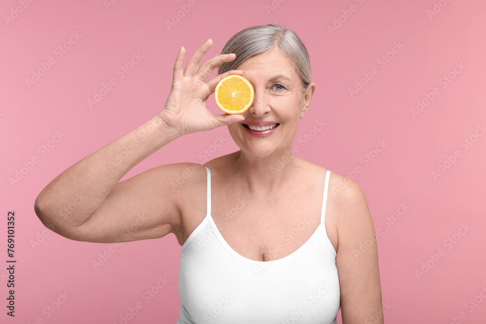 Beautiful woman with half of orange rich in vitamin C on pink background Beautiful woman with half of orange rich in vitamin C on pink background
