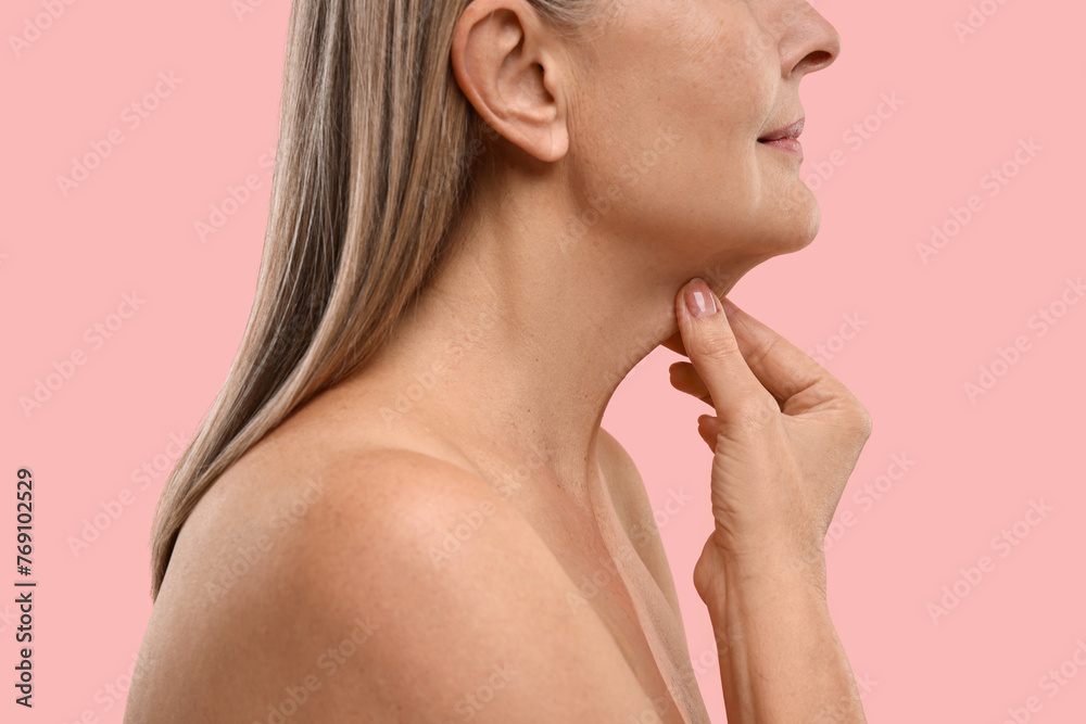 Mature woman touching her neck on pink background, closeup Mature woman touching her neck on pink background, closeup