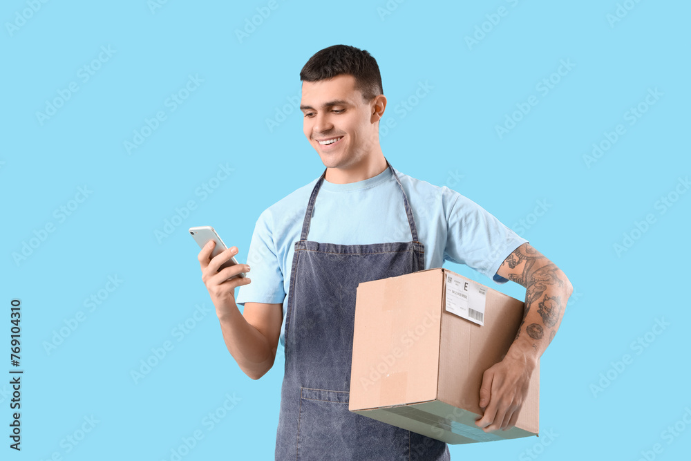 Male online store seller with mobile phone and parcel on blue background Male online store seller with mobile phone and parcel on blue background