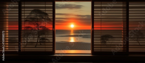 View of the sun setting as it shines through the horizontal blinds on a window, casting a warm glow in the room