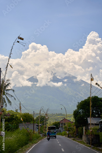 View of the volcano from the road decorated for the holiday in the village. Bamboo decorations along the road. A panorama of Mount Agung covered in clouds.