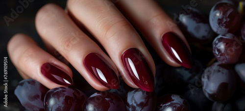 An elegant single-color manicure in deep burgundy, accompanied by the rich hues of ripe grapes photo