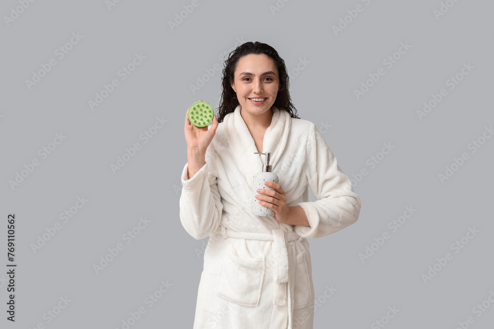 Beautiful young woman with hair scalp massager and shampoo on grey background Beautiful young woman with hair scalp massager and shampoo on grey background