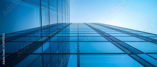 A symmetrical perspective of a glass skyscraper reaching towards a pristine blue sky, epitomizing urban architectural elegance..