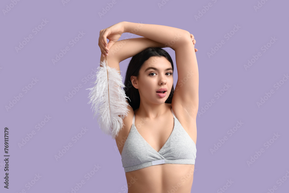 Obraz premium Beautiful young woman with soft feather on lilac background. Epilation concept