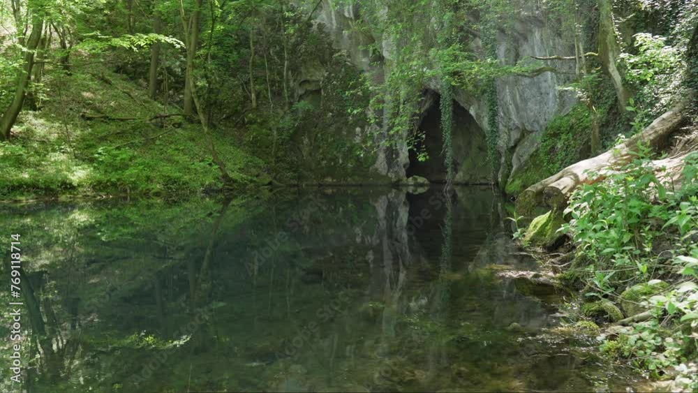 Cave in a mountain on lakeshore hidden behind green foliage Cave in a mountain on lakeshore hidden behind green foliage