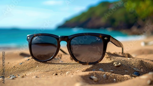 Close-up black sunglasses on sandy beach background photo