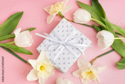 Gift box with beautiful tulips and daffodil flowers on pink background