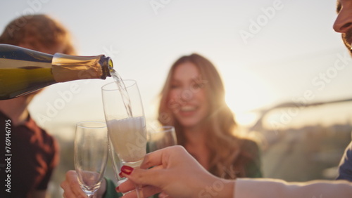 фотографія Colleagues pouring sparkling wine in goblets enjoying time together close up