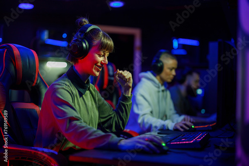 Woman gamer in a gaming club celebrating victory while playing a video game