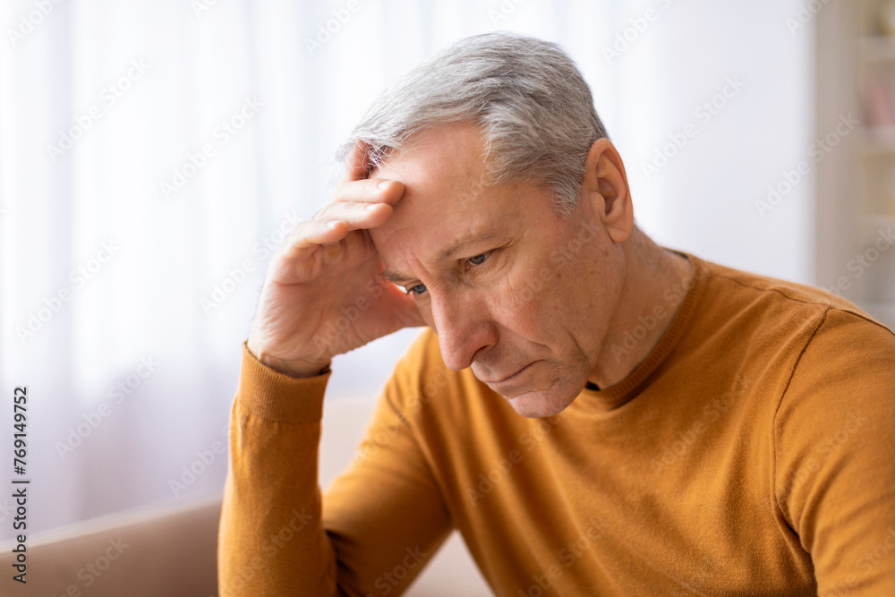 Aged man holds forehead in an upset manner Aged man holds forehead in an upset manner