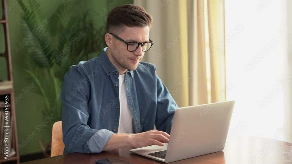 A man with glasses works at home, the workplace uses a computer. Comfortable work online, writes a message to the mail. A man with glasses works at home, the workplace uses a computer. Comfortable work online, writes a message to the mail.