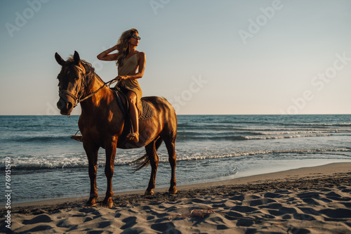 A young attractive woman is enjoying horseback riding at seaside. photo