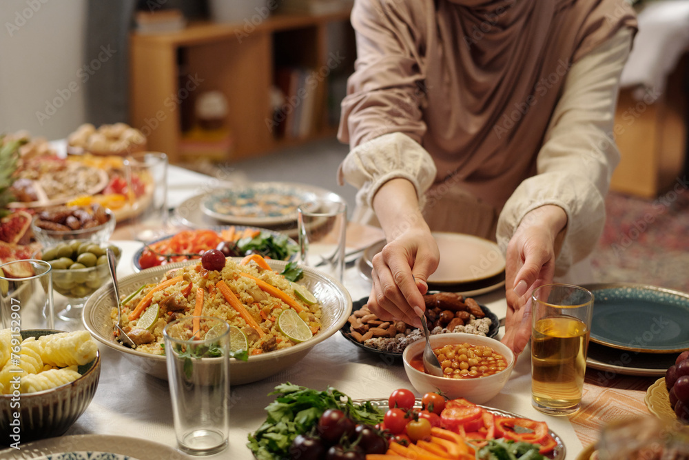 Unrecognizable Woman in Hijab Setting Festive Table For Eid Al-Fitr Unrecognizable Woman in Hijab Setting Festive Table For Eid Al-Fitr